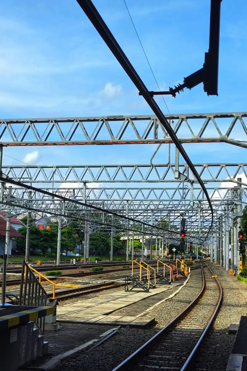 Vías de tren con catenaria y postes de electrificación